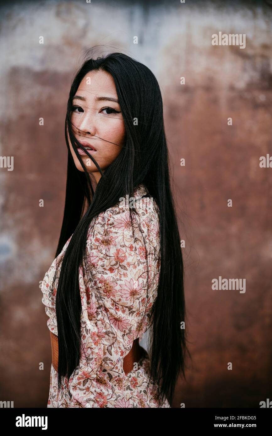 Mujer seria con pelo largo por puerta oxidada Foto de stock