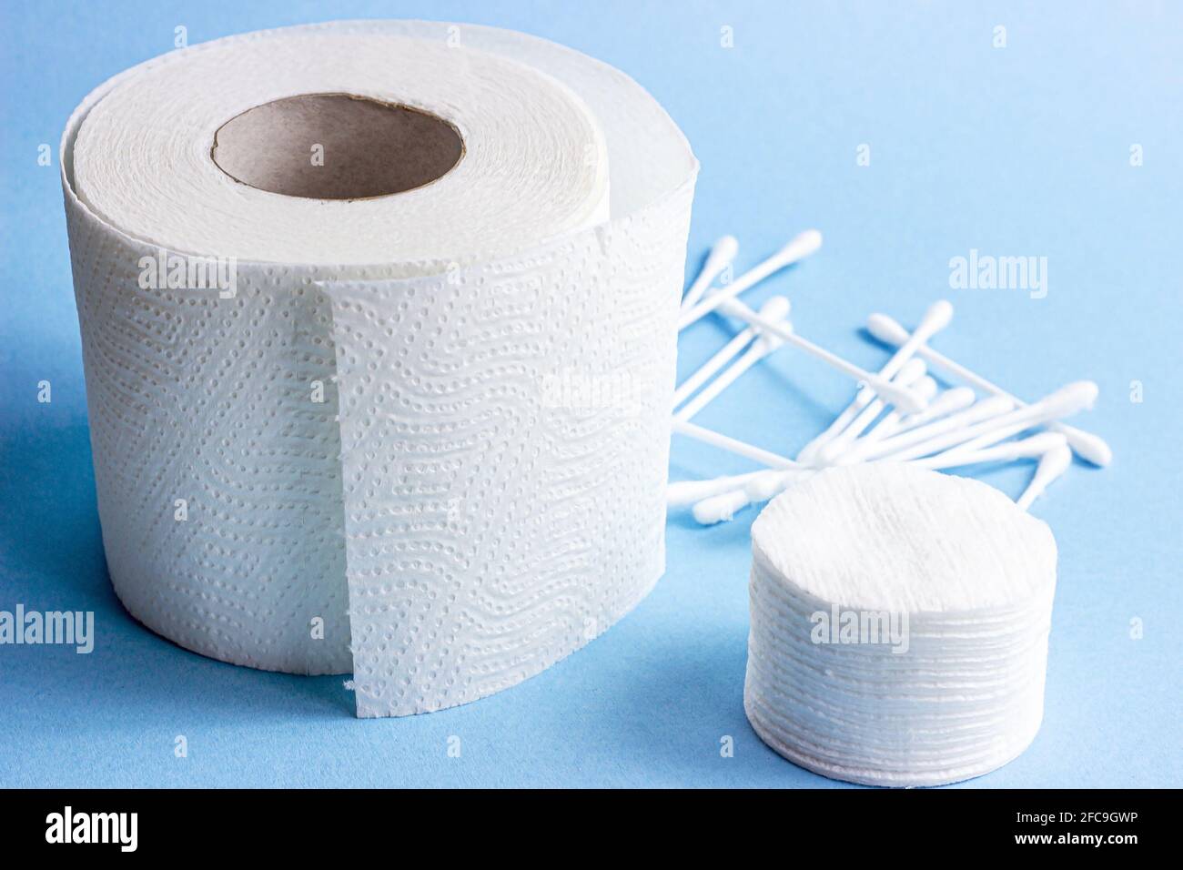 Almohadillas y varillas blancas de algodón suave para higiene y atención  sanitaria y rollo de papel higiénico sobre fondo azul claro Fotografía de  stock - Alamy
