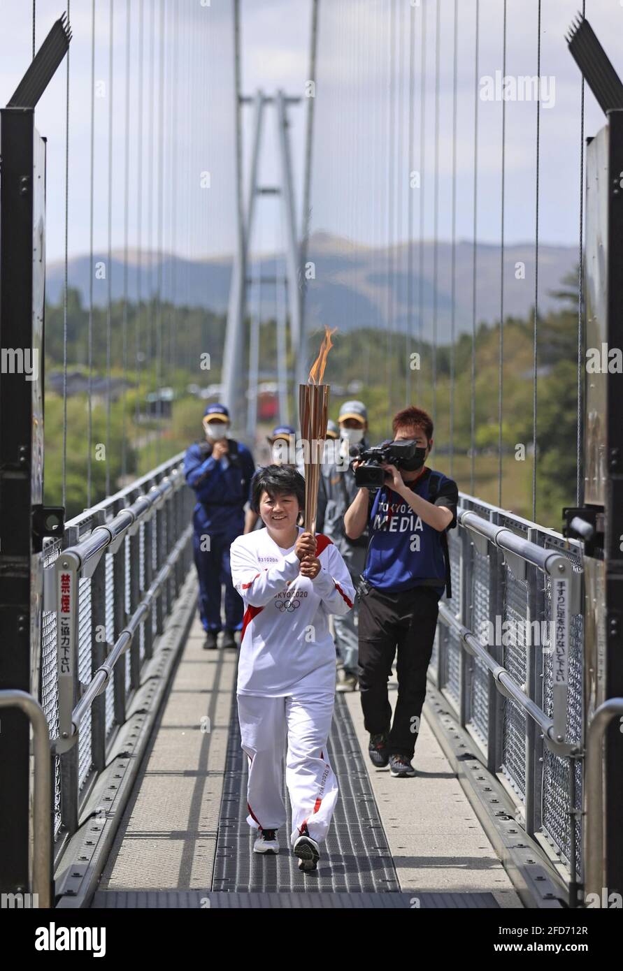 Un corredor de relevo de antorcha olímpica de Tokio cruza un puente colgante  en Kokonoe en la prefectura de Oita, suroeste de Japón, el 24 de abril de  2021. (Kyodo)==Fotografía de Kyodo