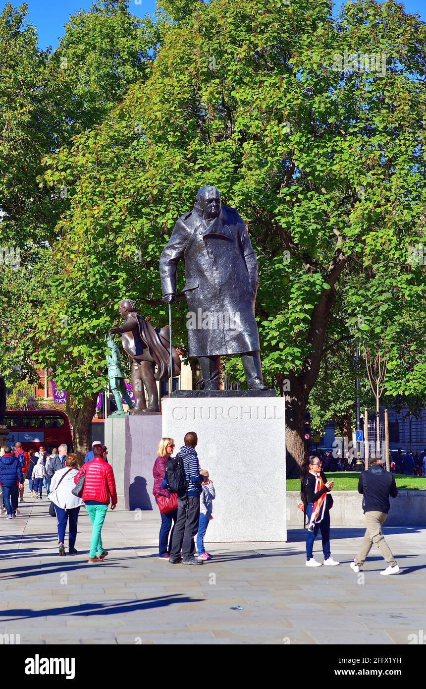 Londres, Inglaterra, Reino Unido. Los turistas en y alrededor de una estatua de Winston Churchill en la Plaza del Parlamento cerca de las Casas del Parlamento. Foto de stock