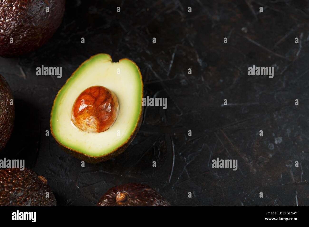 Aguacate Hass en rodajas y orgánico entero sobre fondo negro. Una