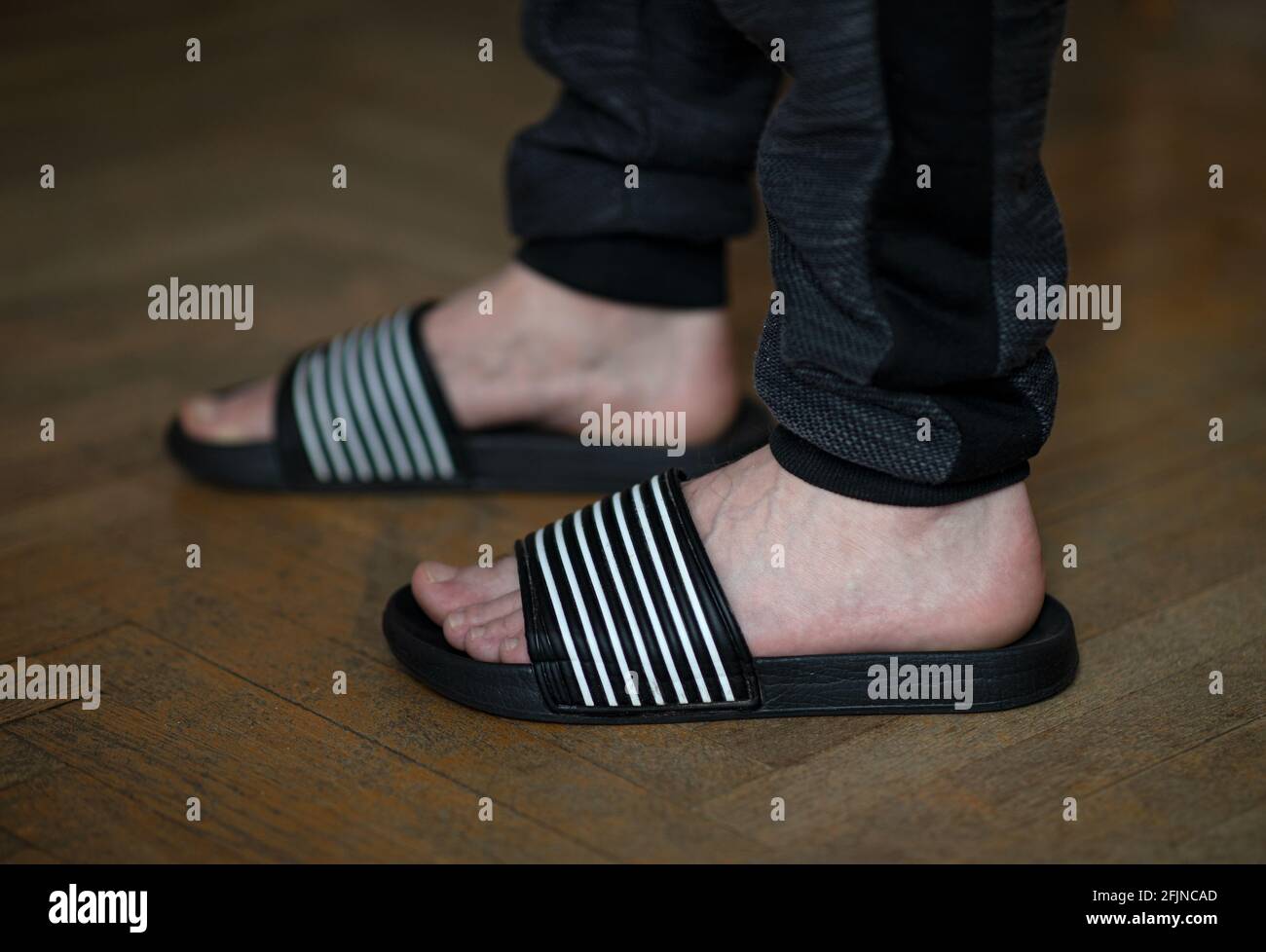 Primer plano de los pies masculinos en chanclas en casa el suelo de madera  Fotografía de stock - Alamy