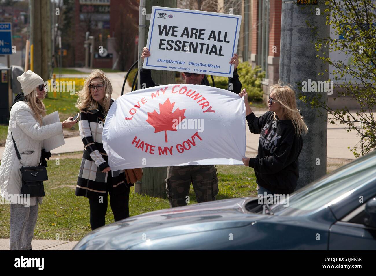 Vaughan, Canadá - 25 de abril de 2021: Personas que sostienen banderas Todos somos esenciales y el amor de mi país odio mi gobierno que protesta COVID-19 me cerró Foto de stock