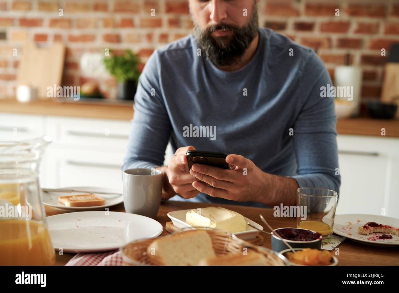 Primer plano del hombre usando el teléfono móvil durante el desayuno Foto de stock