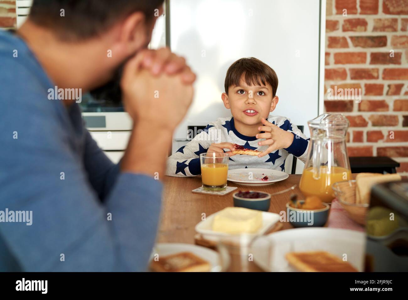 Padre e hijo hablando juntos en el desayuno Foto de stock