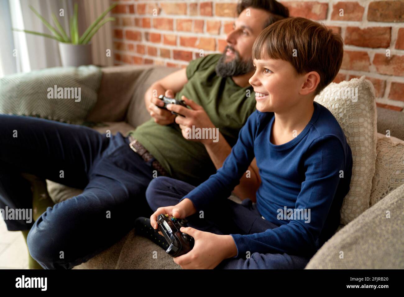 Padre e hijo sentados en casa y jugando a videojuegos Foto de stock