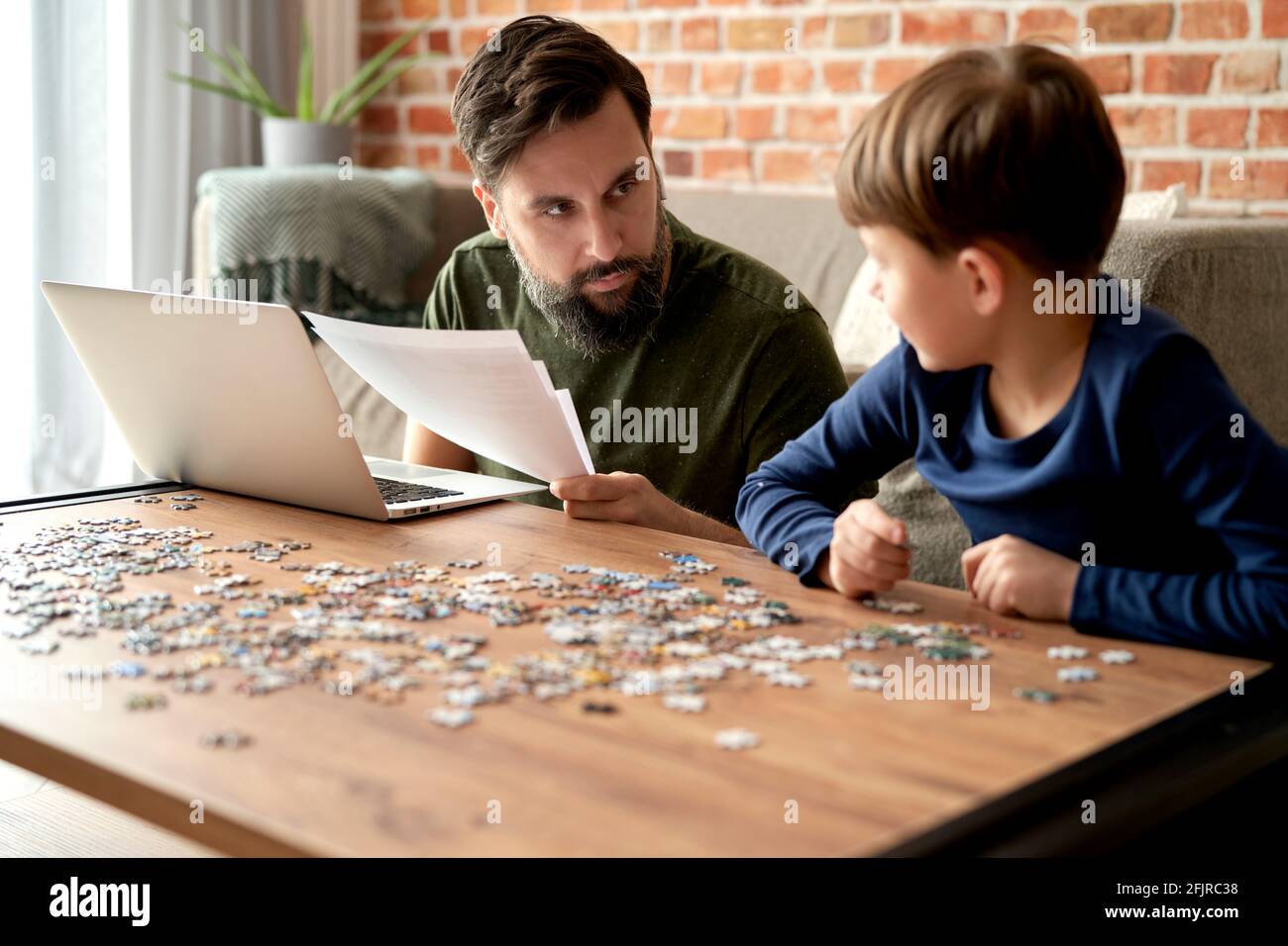 Padre trabajando y el hijo resolviendo rompecabezas Foto de stock