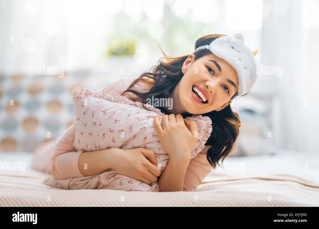 Hermosa mujer joven está despertando en el dormitorio en casa. Foto de stock