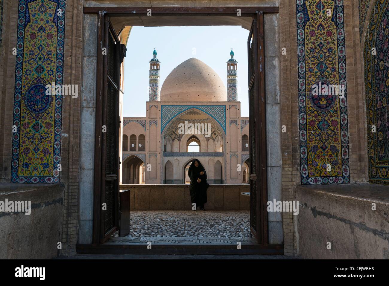 Contemple una mezquita adyacente al Gran Bazar de Kashan con una mujer en chador negro. Irán. Foto de stock