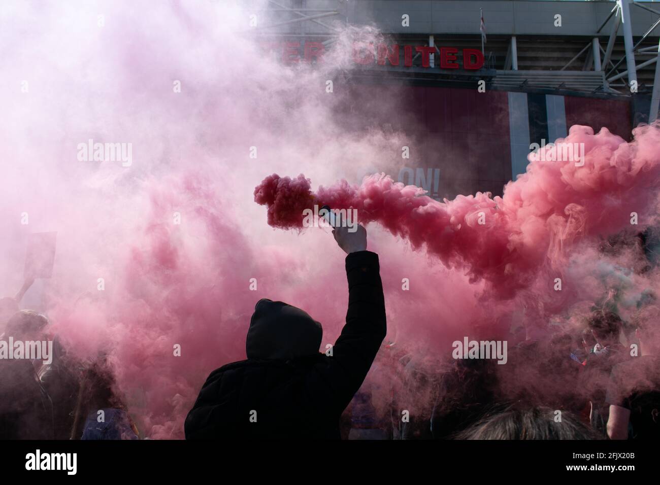 Protesta contra Glazer en el campo de fútbol Old Trafford. Apoyo que sostiene la llamarada de humo rojo. Estadio del Manchester United, Reino Unido. Foto de stock