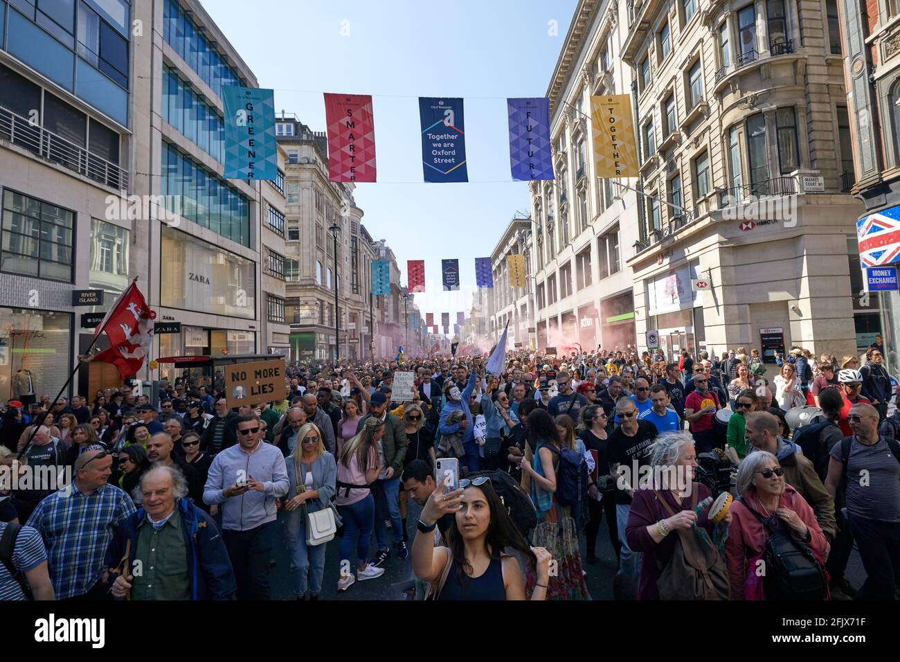 Londres, Reino Unido - 24 Apr 2021: Una dama toma un selfie delante de miles de personas que llenaron Oxford Street en una marcha pidiendo un levantamiento de todas las restricciones del coronavirus. Foto de stock