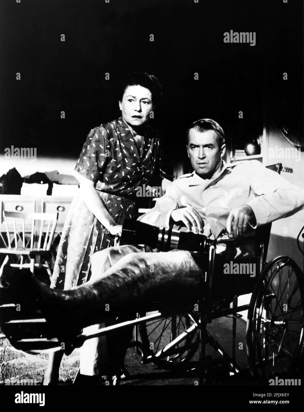1954 , Estados Unidos : El actor James STEWART ( 1908 - 1997 ) y THELMA RITTER en LA VENTANA TRASERA ( La finestra sul cortile ) Por ALFRED HITCHCOCK - CINE - triller - pigiama - pajama - gamba ingessata rotta - ingessatura - frattura - sedia a rotelle - teleobiettivo - macchina fotografica - fotografo - fotógrafo - cámara fotográfica - brocken enguantado - fractura - invalido - discapacitado - silla de ruedas -- -- Archivio GBB Foto de stock