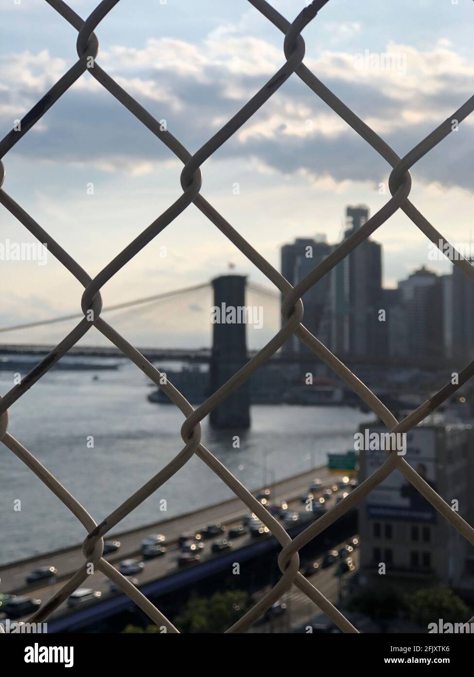 Vista borrosa de la ciudad de Nueva York, el Puente de Brooklyn y el río East a través de una valla. FDR Drive en la frontera. Foto de stock