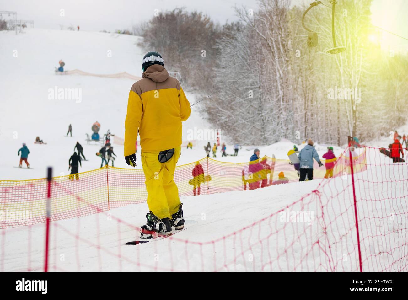 Snowboarder en amarillo traje de esquí levante se levanta sobre la ladera de montaña. Deportes de esquí en invierno. Vacaciones en las montañas de esquí. Foto de stock