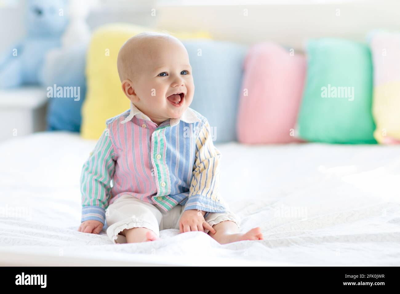 Niño pequeño en dormitorio blanco. Niño recién nacido en la cama con cojines  de color pastel. Guardería infantil. Textil, almohadas y ropa de cama para  niños Fotografía de stock - Alamy