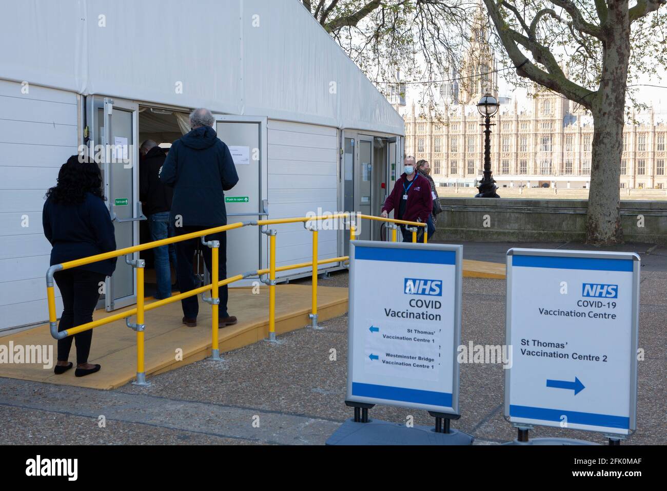 Londres, Reino Unido, 27 de abril de 2021: La gente hace cola en el punto final de un centro de vacunación en los terrenos del Hospital St Thomas, frente a las Casas del Parlamento en la orilla opuesta del río Támesis. El primer ministro Boris Johnson todavía se enfrenta a acusaciones de haber preferido que 'los cuerpos se amontonan' en lugar de tener un tercer cierre. Anna Watson/Alamy Live News Foto de stock