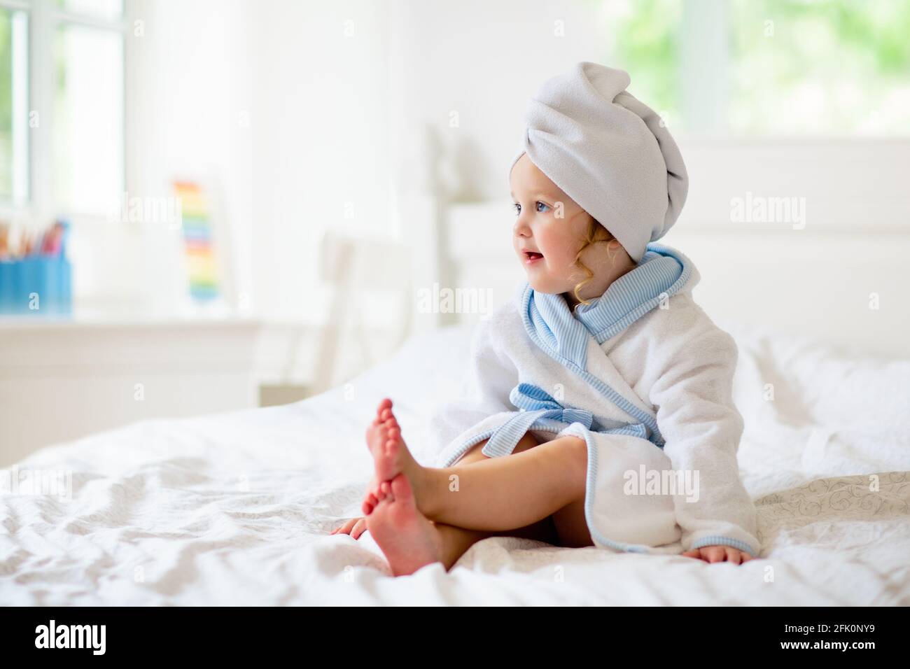 Niña en toalla después del baño. Cuidado infantil. Niño pequeño envuelto en  una bata cálida después de la ducha. Lavó a un niño limpio en la cama antes  de dormir. Ropa de