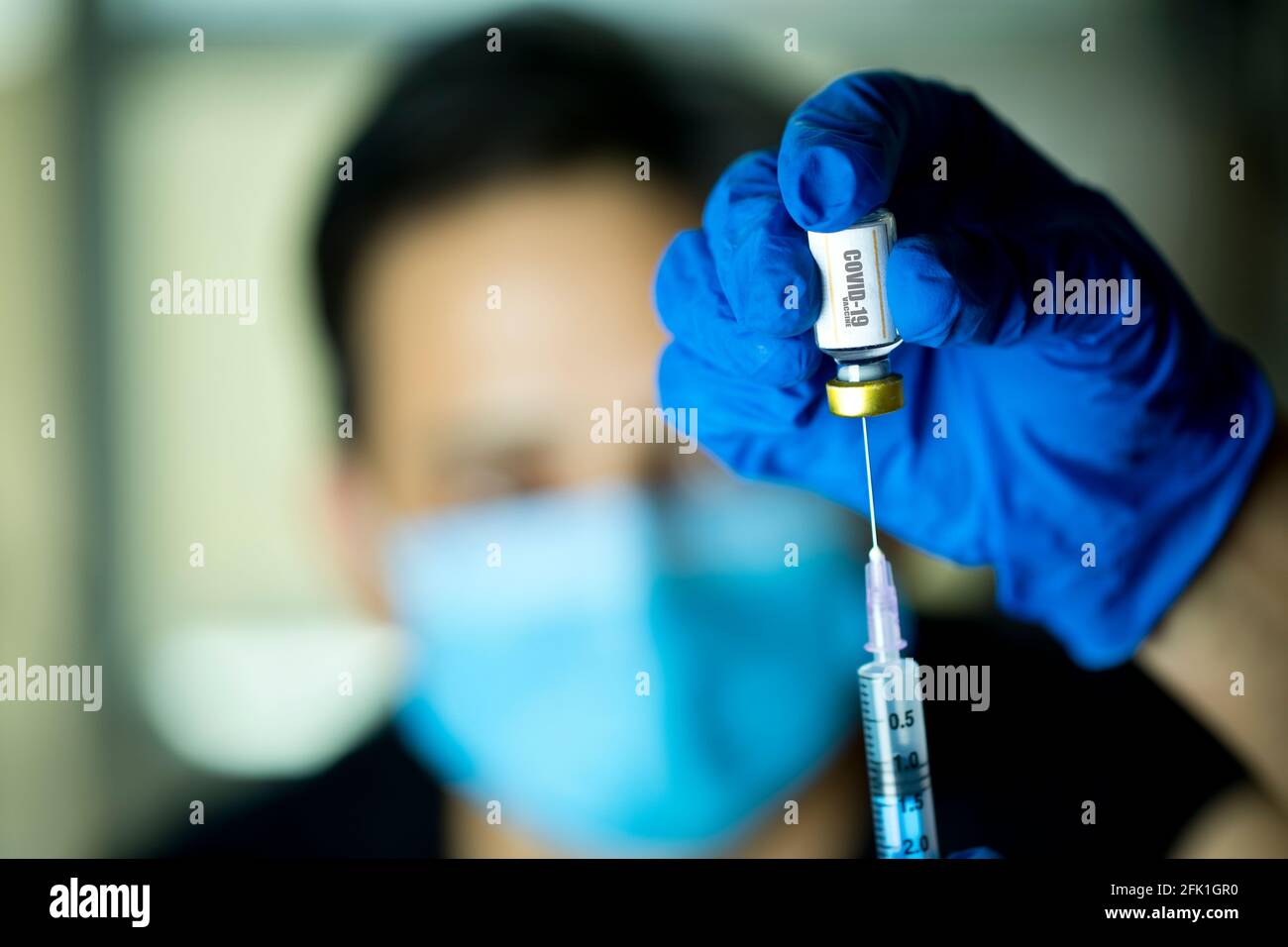 El médico extrae el líquido de la vacuna del vial para vacunar al hombre Foto de stock