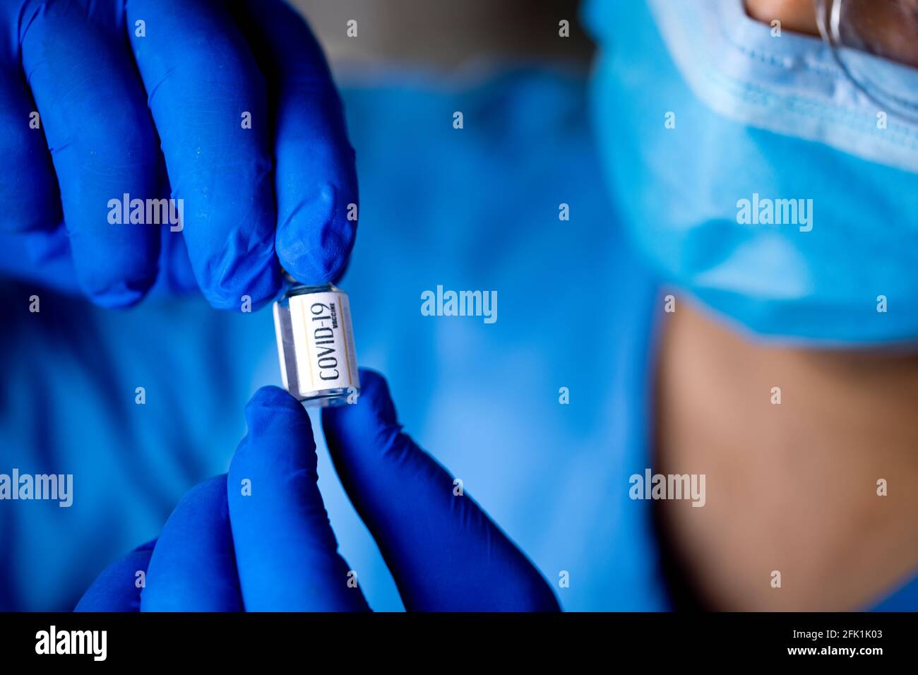 Médico que sostiene y mira la vacuna covid-19 en el hospital Foto de stock