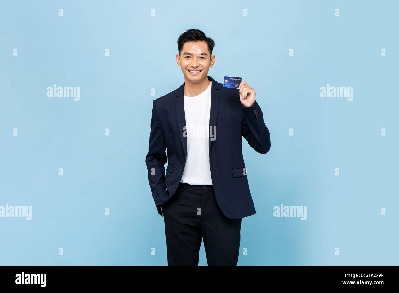 Bonito hombre del sudeste asiático en semi formal blazer holding tarjeta de  crédito en fondo de estudio aislado de color azul claro Fotografía de stock  - Alamy