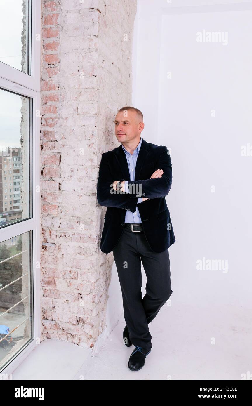 Hombre con camisa azul, pantalón negro y chaqueta azul sobre fondo de pared  de ladrillo Fotografía de stock - Alamy