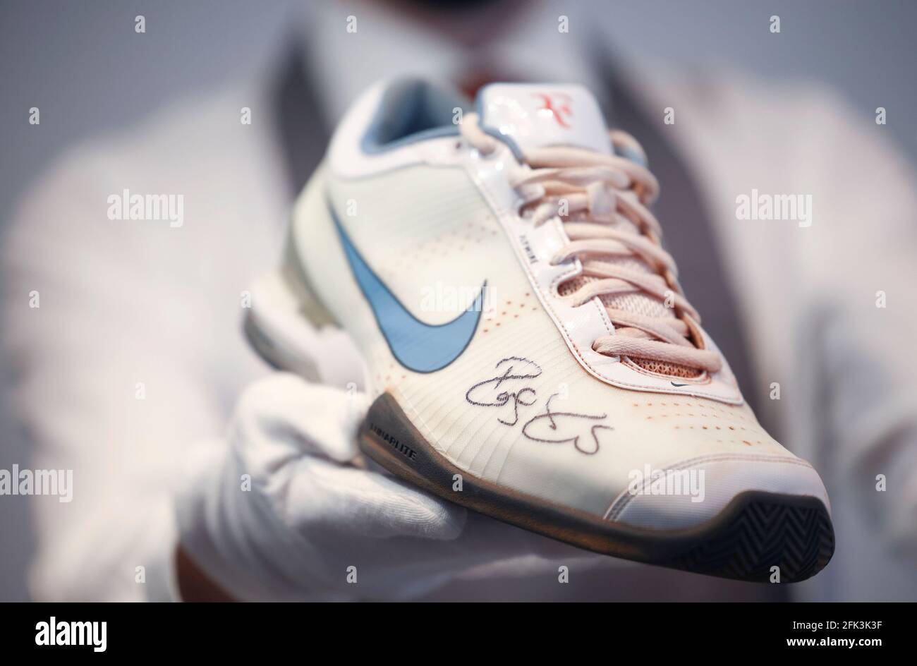 Un asistente de la galería de Christie posará con zapatillas de deporte del  lote 'French Open, 2009' incluido en 'The Roger Federer Collection', que se  venderá en subasta, en Christie's Auction House