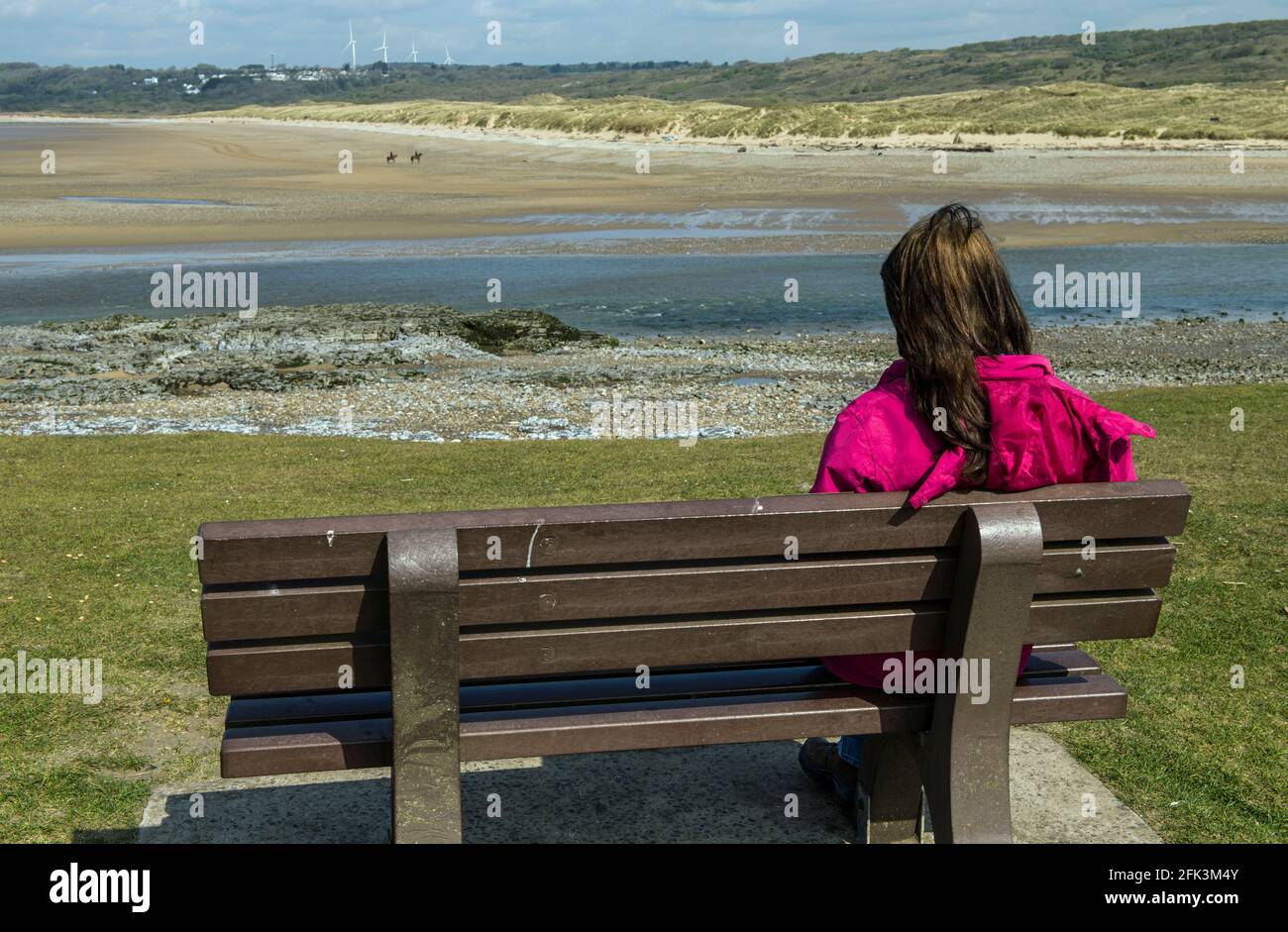 Señora mirando al otro lado del estuario del río Ogmore en Ogmore by Sea en la Costa de la Herencia de Glamourgan, al sur de Gales Foto de stock