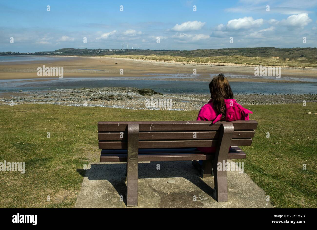 Señora mirando al otro lado del estuario del río Ogmore en Ogmore by Sea en la Costa de la Herencia de Glamourgan, al sur de Gales Foto de stock