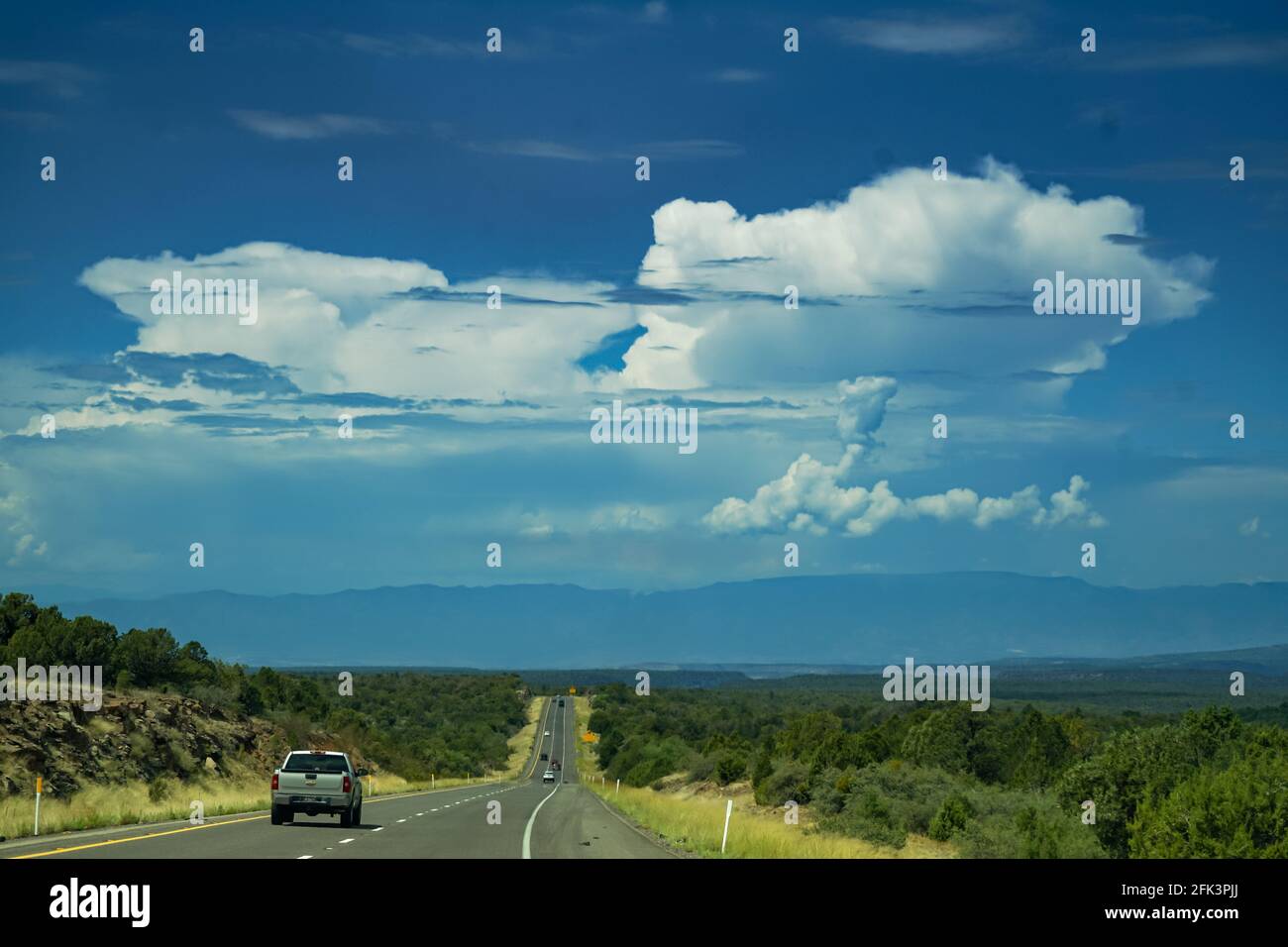 Carretera perfectamente recta que conduce al horizonte y a una enorme nube de truenos en el cielo Foto de stock