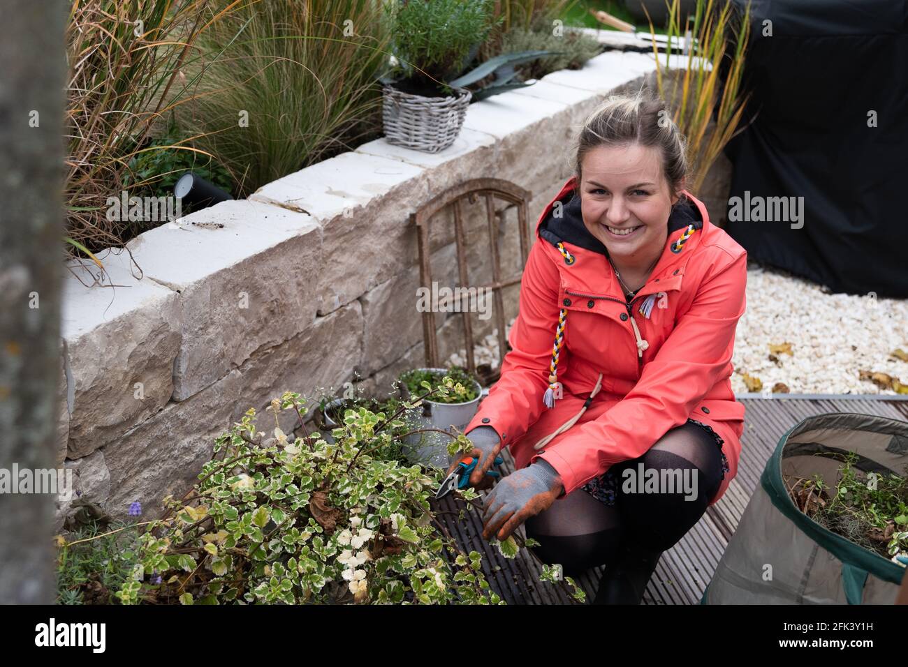 Atractiva mujer rubia trabajando en el jardín, cortando plantas y foie gras Foto de stock