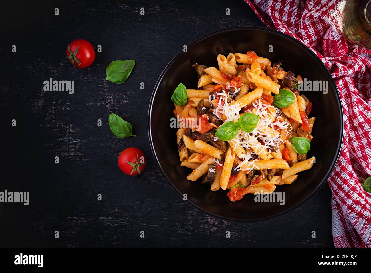 Pasta penne con berenjena. Pasta alla normal - comida tradicional italiana con berenjena, tomate, queso ricotta y albahaca. Vista superior, techo, espacio de copia Foto de stock