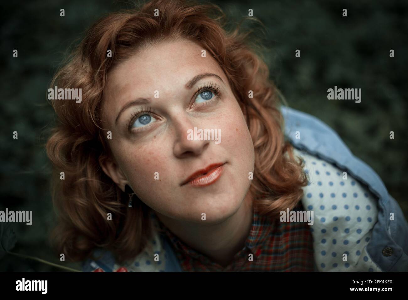 Una mujer rubia con ojos azules mira hacia arriba. Retrato grande. Foto de stock