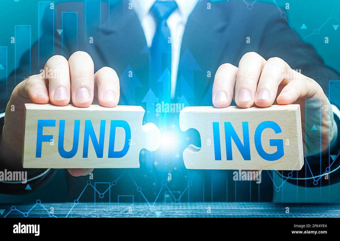 Businessman conecta rompecabezas con la palabra financiación. Invertir en un proyecto empresarial, recaudar fondos. Proporcionar recursos financieros. Crédito, donaciones, Foto de stock