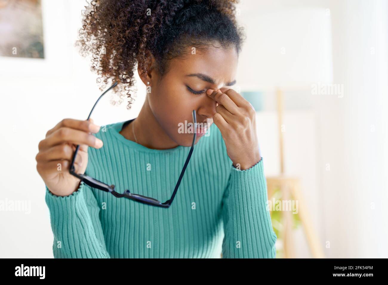 Una mujer africana cansada y sobrecargada de trabajo sosteniendo gafas sintiendo tensión ocular Foto de stock