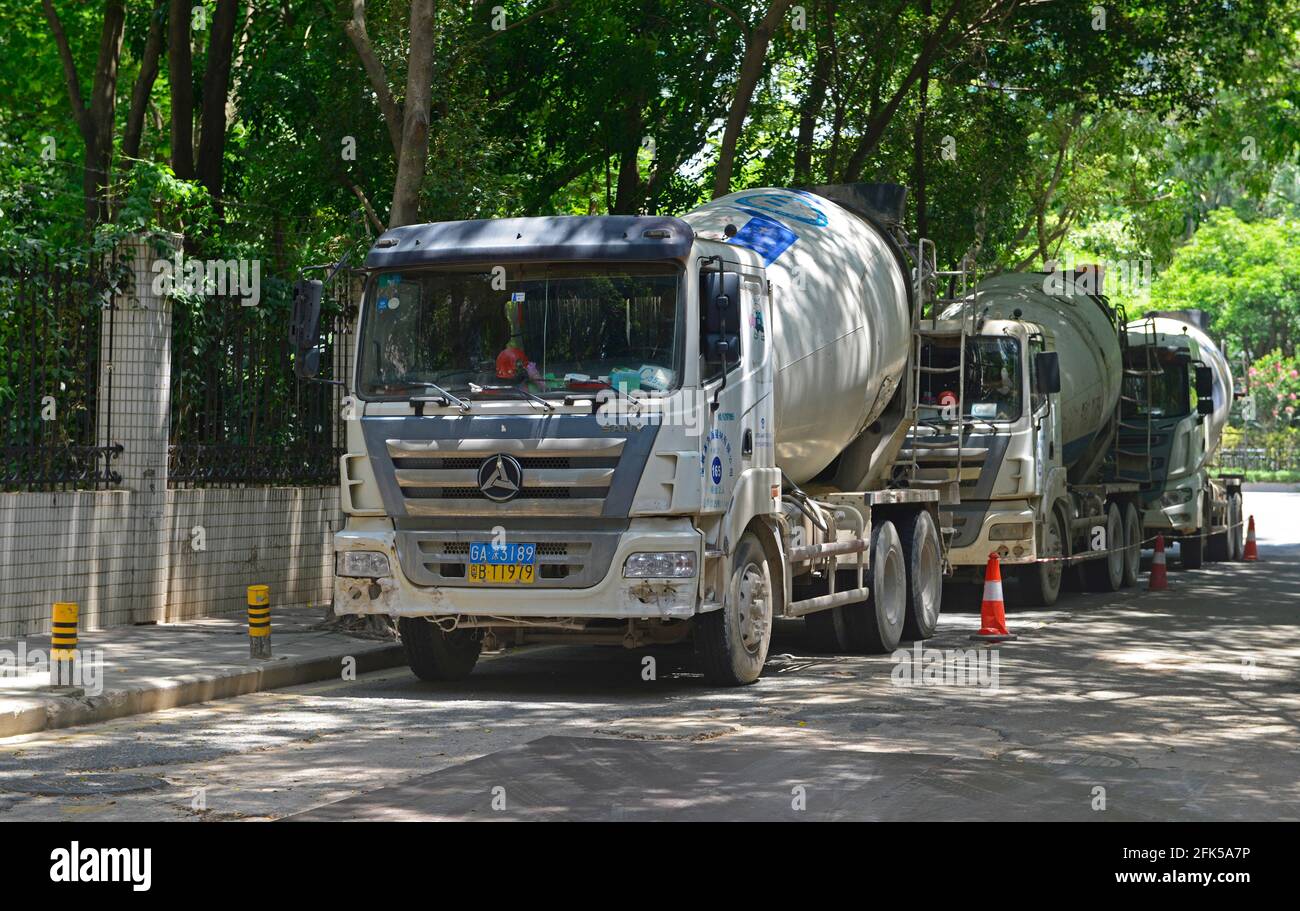 Tres mezcladores de cemento estacionados en una calle sombreada en Shenzhen, China Foto de stock
