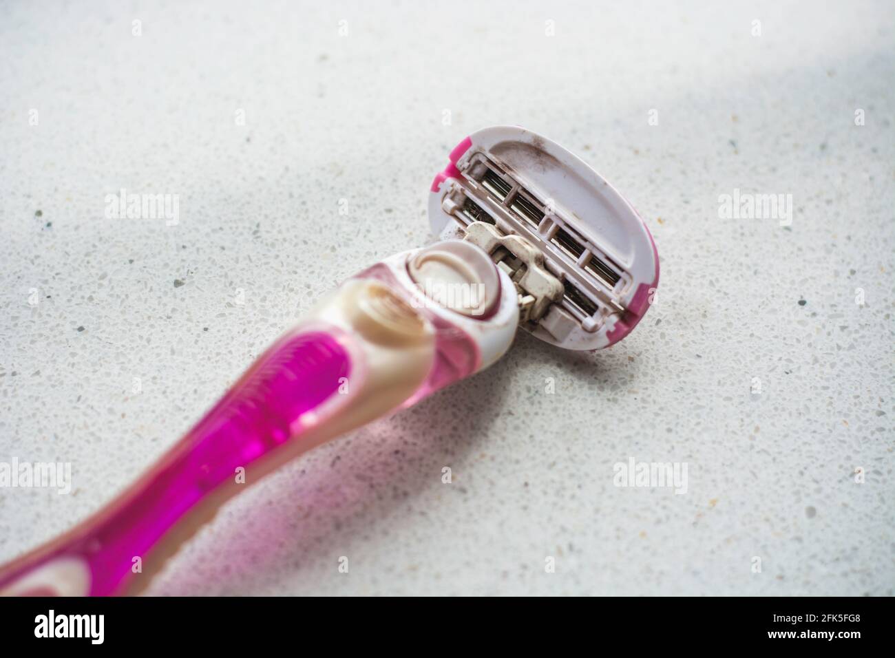 Afeitadora para mujer rosa, bien usada, sucia y oxidada. Higiene personal y concepto antisanitario Foto de stock