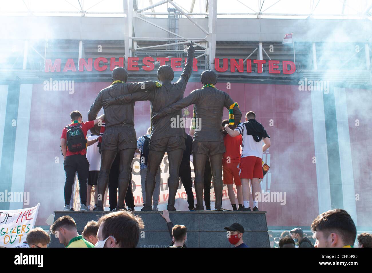 Protesta contra Glazer en el campo de fútbol Old Trafford . El defensor se paró en la estatua de la Trinidad rodeada de humo. Estadio del Manchester United, Reino Unido Foto de stock