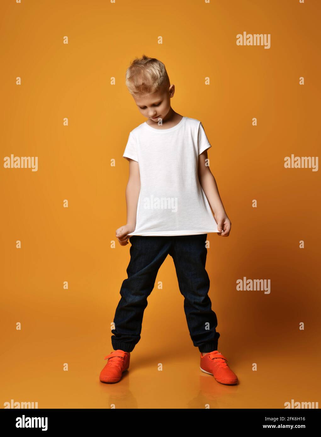 Diseño de camisetas y concepto de publicidad: un niño sonriente con una camiseta  blanca en blanco apuntándose a sí misma