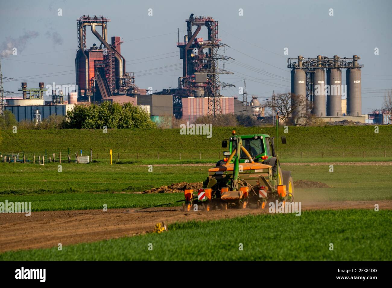 Agricultor que trabaja en el campo, Duisburg-Baerl, sembrando, al fondo, el alto horno ThyssenKrupp Steel Steelworks, Duisburg, NRW, Alemania Foto de stock