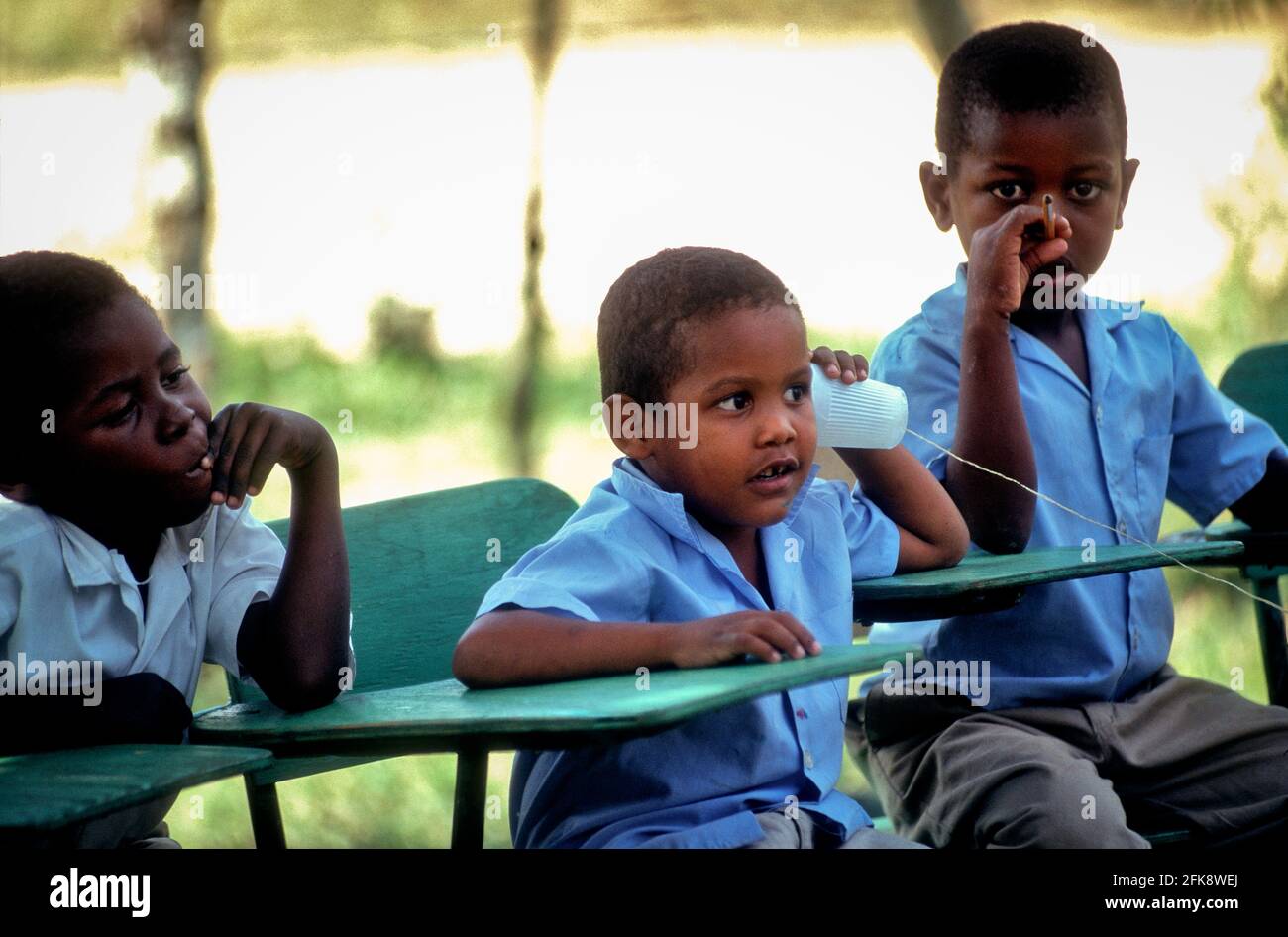 Dominikanische Republik, Schulkinder einer Freiluftschule en Cruz Verde spielen telefonieren. Foto de stock