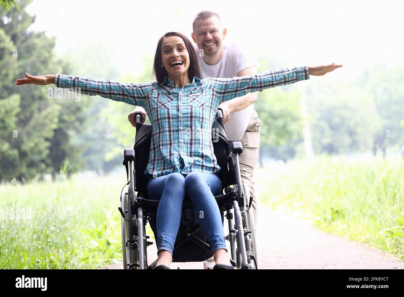 Guy lleva a la mujer alegre en silla de ruedas de cerca Fotografía de stock  - Alamy