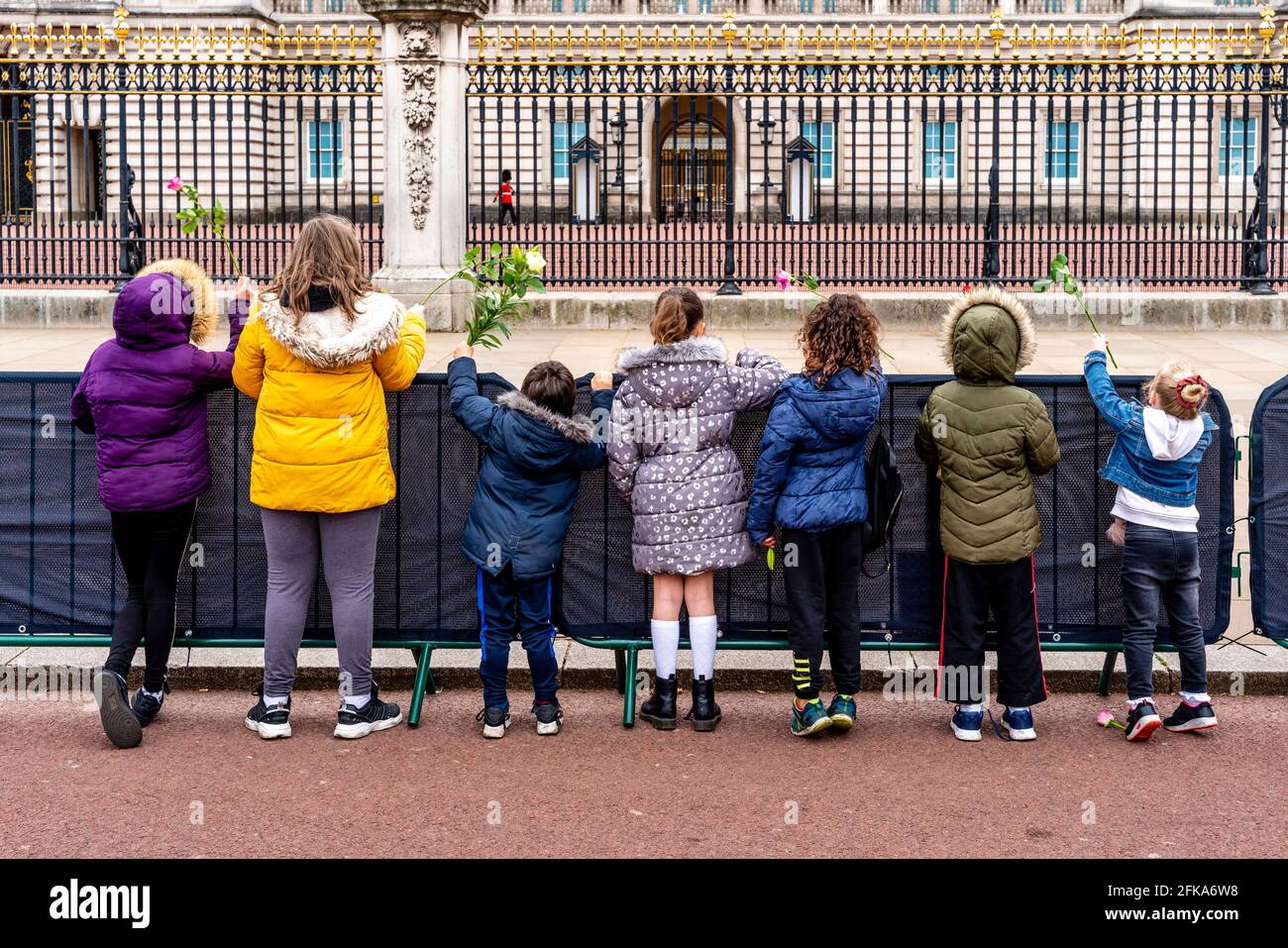 Un grupo de niños británicos esperan para poner flores en las puertas del Palacio de Buckingham después de la muerte del príncipe Felipe, Londres, Reino Unido. Foto de stock