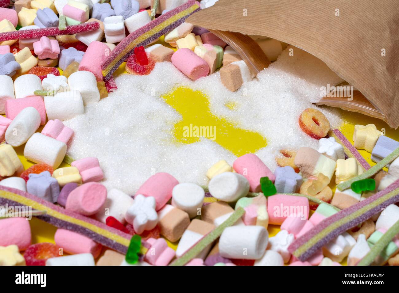 el problema del consumo excesivo de azúcar. el azúcar se derrama de la bolsa, muchos dulces y malvaviscos, espacio para texto Foto de stock
