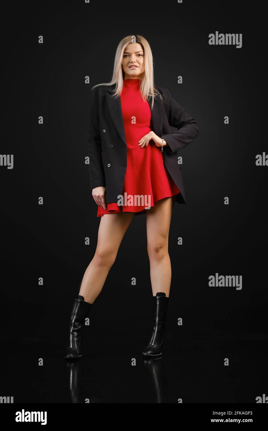 Bonita mujer con vestido rojo y chaqueta negra posando adentro estudio  oscuro Fotografía de stock - Alamy
