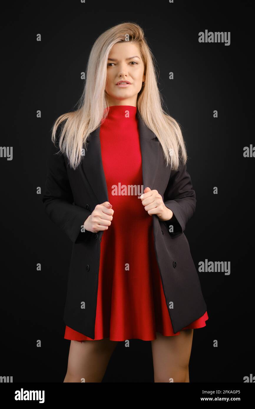 Bonita mujer con vestido rojo y chaqueta negra posando adentro estudio  oscuro Fotografía de stock - Alamy
