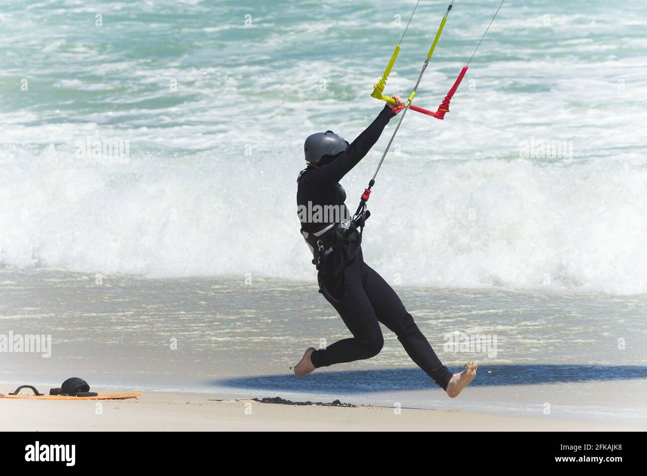 kitesurfer corriendo en la arena en una playa mientras se sostiene en el mango del arnés en el concepto de viento fuerte deportes acuáticos estilo de vida Foto de stock