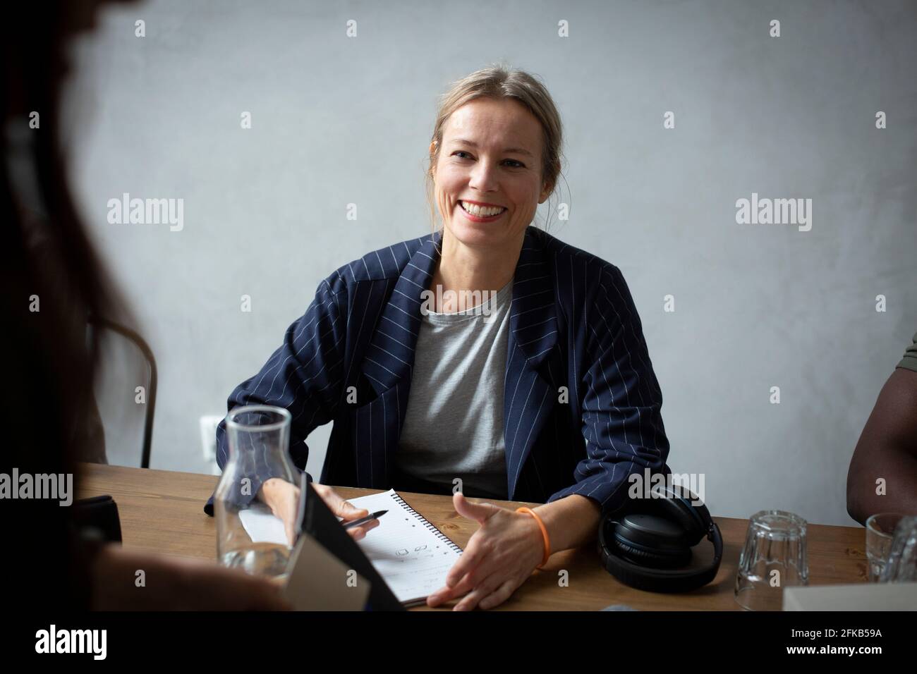Mujer de negocios sonriente discutiendo con su colega en el escritorio en la oficina creativa Foto de stock