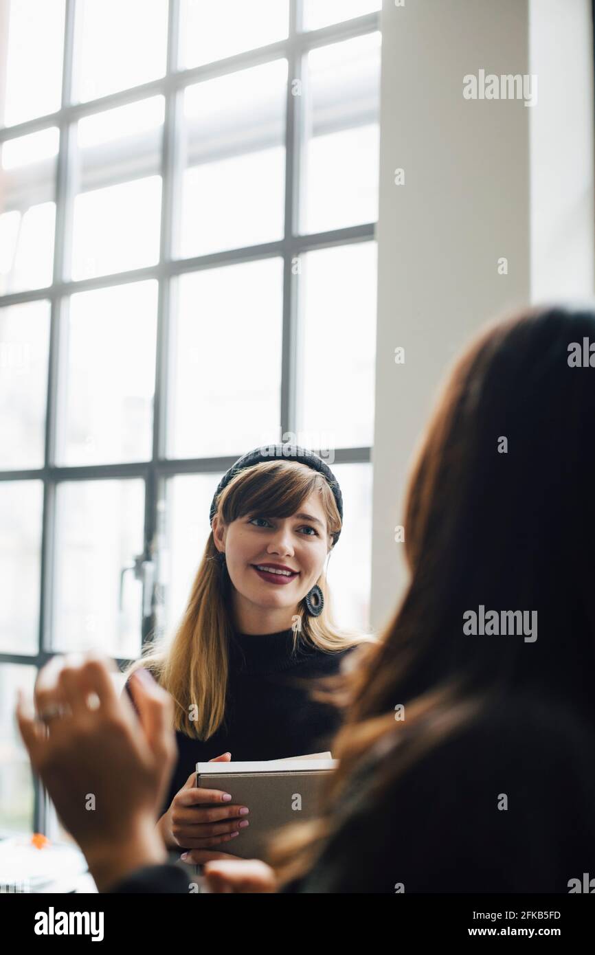 Mujer de negocios sonriente hablando con una colega en el cargo Foto de stock