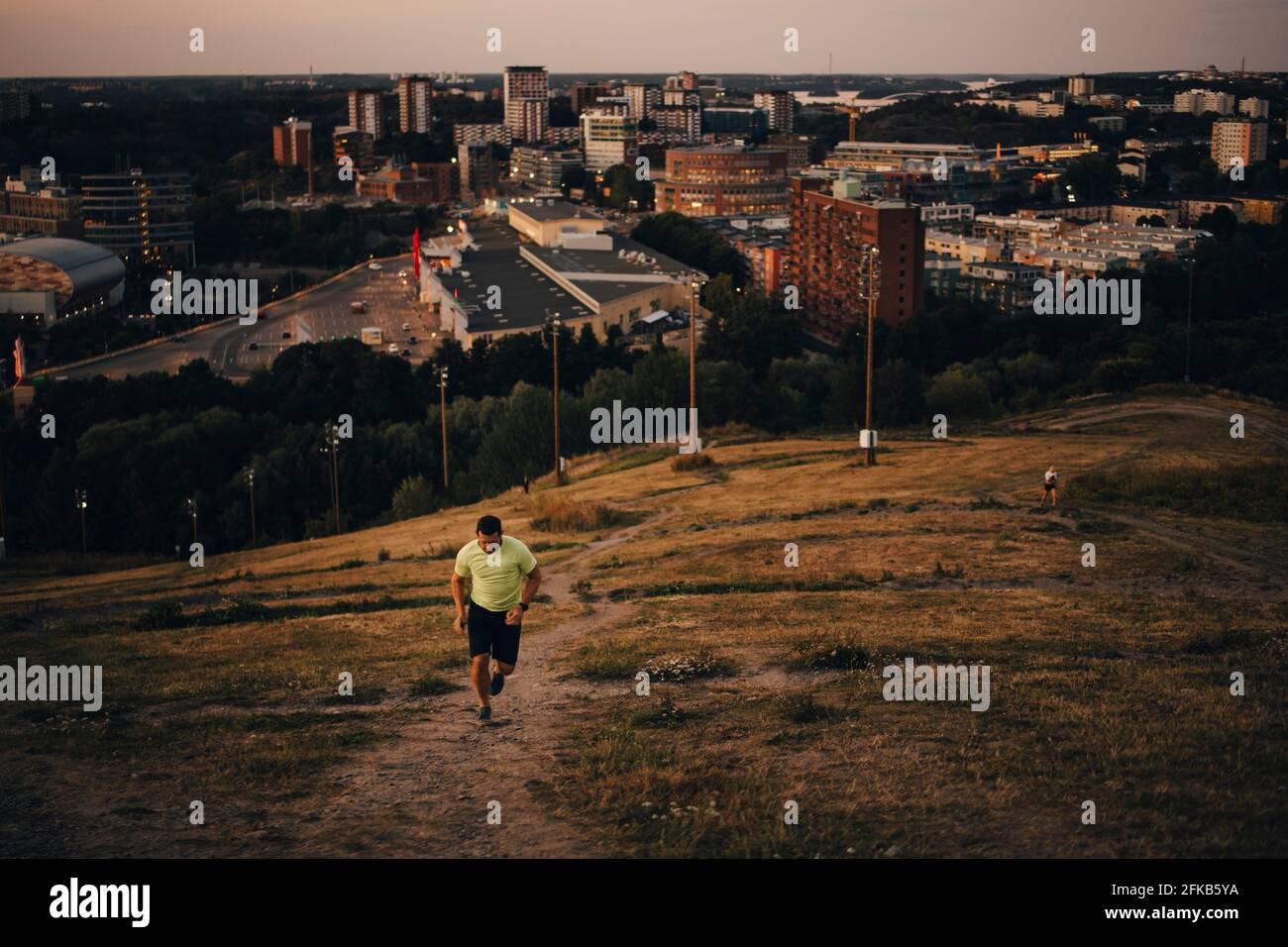 Sportsman correr en tierra contra la ciudad durante la puesta de sol Foto de stock