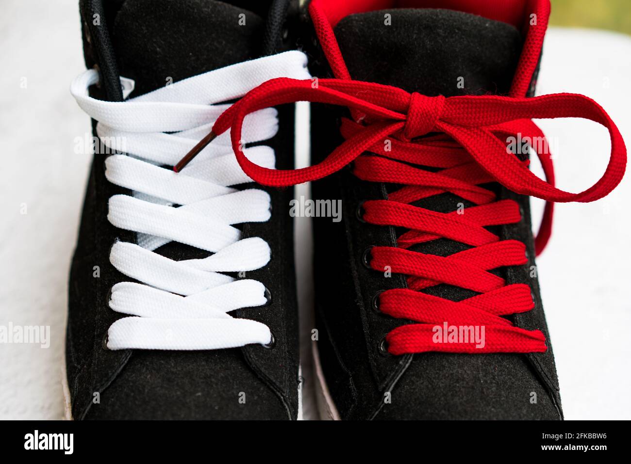 Un par de zapatos deportivos negros con cordones de diferentes colores:  Blanco y rojo Fotografía de stock - Alamy